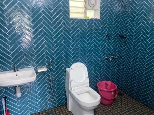 a bathroom with a white toilet and a sink at SOLITUDE Riverside Holiday Home in Vallikunnu