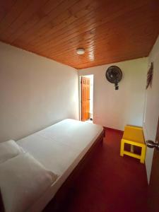 a bedroom with a white bed and a yellow stool at Chalet Natalia Montenegro Quindío in Montenegro