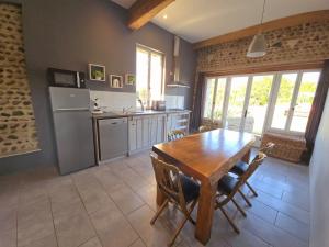 a kitchen with a wooden table and a refrigerator at La parenthèse de Saint Esselin 2 in Larreule