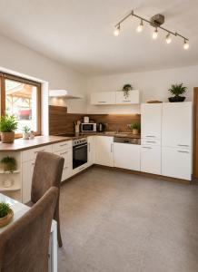 a large kitchen with white cabinets and a table at Ferienwohnung Biohof Untermar in Obervellach +24 photos
