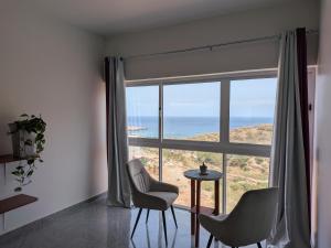 a room with a large window with a table and chairs at Mirage in Tarrafal