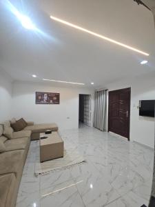 a large living room with a couch and a tv at Bedroom Jimi in Al Ain