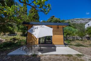 a small cabin with a table and chairs and an umbrella at Apartments Giardino Mediterraneo in Petrovac na Moru