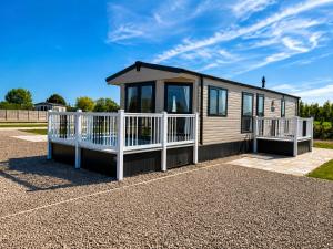 a tiny house on a gravel lot with a white fence at Parkside Fishery in Skegness