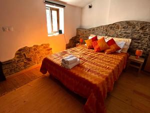 a bedroom with a large bed with a stone wall at Casas dos Carregais in Carregais