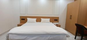 a bedroom with a large white bed with a wooden headboard at Dev Palace in Saharsa