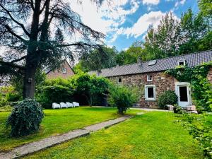 a stone house with white chairs in the yard at Maison de gesves in Gesves