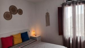 a bedroom with a bed with colorful pillows and a window at Casa María in Mojácar
