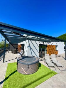 a covered patio with chairs and a grill on grass at Apartmán Raj in Rajecké Teplice