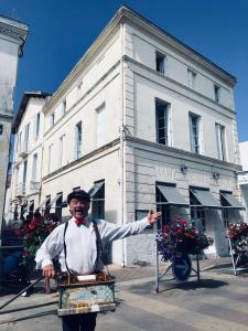 a man is standing in front of a building at Hôtel Le Galet Bleu in Fouras