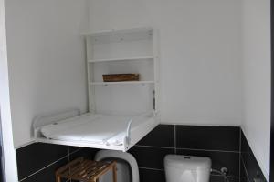 a bathroom with a toilet and a white shelf at O Ptit home in Saint-Vincent-sur-Jard