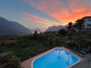 a swimming pool with a sunset in the background at Glicine in Carlazzo