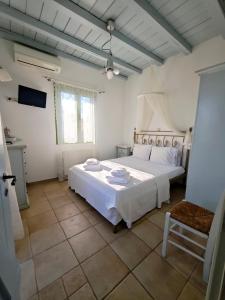 a bedroom with a large white bed and a chair at KLIMA apartment in Perdika