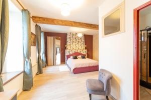 a bedroom with a bed and a chair at L Ancestral in Beaumont-les-Autels