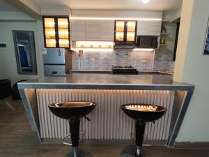 a kitchen with a counter with two bar stools at DEPPIu in Piura