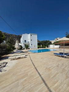 a pool with chairs and umbrellas next to a building at Paradise Matala Hotel in Matala