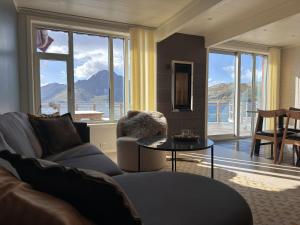 a living room with a couch and a table and windows at Modern seafront cabin with sauna 8 mins to Leknes in Storeidet