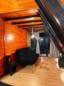 a living room with a black couch and wooden walls at Chalets Nisa- lago de tota in Tota +51 photos