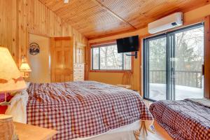 a bedroom with two beds and a television in a cabin at Dock & Beach Access: Scenic Lake Ossipee Cabin! in Center Ossipee
