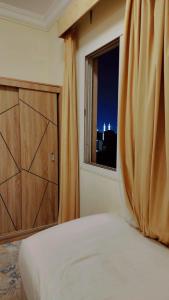 a bedroom with a bed and a window with a curtain at فندق نسك الفضيلة in Ajyad