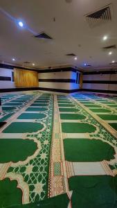 a large room with a green floor with a pattern at فندق نسك الفضيلة in Ajyad +1 photo
