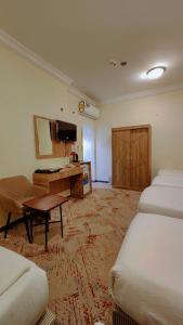 a hotel room with two beds and a desk at فندق نسك الفضيلة in Ajyad