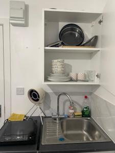 a kitchen counter with a sink and a shelf with dishes at Private studio with a private bathroom and kitchenette in Edmonton
