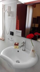 a bathroom sink with a red flower in a vase on it at Corte Degli Estensi in Formigine +42 photos