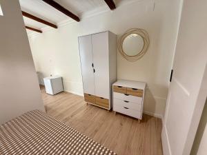 a bedroom with a white cabinet and a mirror at La Maison Fleurie in San Nicola Arcella