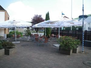a patio with tables and chairs with umbrellas at Hotel Stadt Baunatal in Baunatal