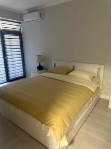 a white bedroom with a large bed with yellow sheets at Modern Apartment Constanța in Constanţa +3 photos