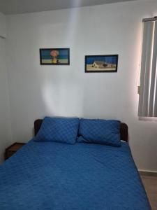 a bedroom with a blue bed with two pictures on the wall at relax en tucacas in Boca de Aroa