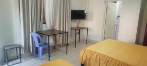 a bedroom with a bed and a desk and a television at Hostal Cadena in Tupiza