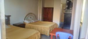 a small room with two beds and a table at Hostal Cadena in Tupiza