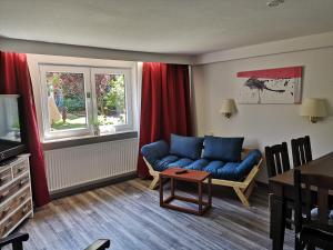 a living room with a blue couch and a table at Hotel Brandaris in Langeoog