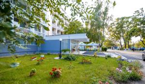 a building with a yard with flowers in the grass at Hotel Semiramis in Saturn