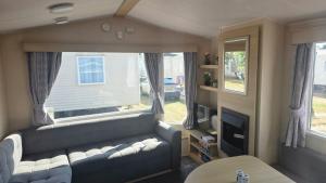 a living room with a couch and a window at california cliffs caravan 2 dunlin in Scratby
