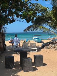 a man walking on a beach with boats in the water at Diving Club Beach Resort in Trincomalee
