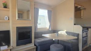 a small living room with a couch and a table at california cliffs caravan 2 dunlin in Scratby