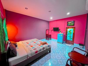 a bedroom with a bed and a pink wall at โชติอนุสรณ์ รีสอร์ท ชุมพร in Ban Bang Mak (1)