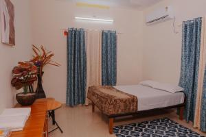 a bedroom with a bed and curtains and a table at The Villa Mahogany in Trivandrum