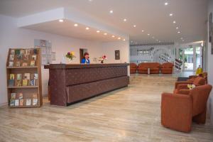 a woman standing at a counter in a waiting room at Hotel Semiramis in Saturn +20 photos