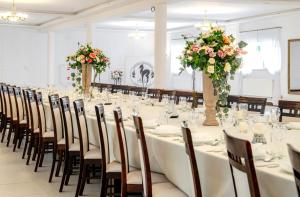 a long table with white tables and chairs and flowers at Gościniec Sarnówka 