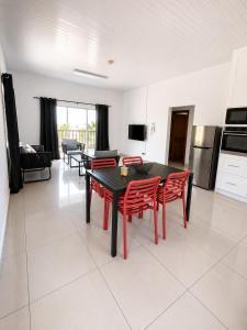 a living room with a black table and red chairs at Trwa Koko Self-catering in Grand'Anse Praslin