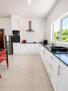 a white kitchen with white cabinets and a large window at Trwa Koko Self-catering in Grand'Anse Praslin