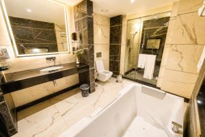 a bathroom with a tub and a sink and a toilet at Hotel Space Crest in Faisalabad