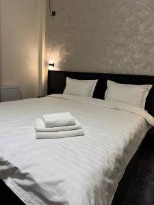 a large white bed with two towels on it at shahrisabz city hotel in Shahrisabz