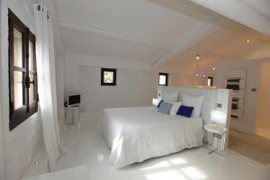 a white bedroom with a large white bed with blue pillows at La bergerie de Nano in Beaumes-de-Venise