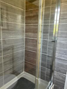 a shower with a glass door next to a toilet at Shepherds Hut (Benny's) in Cullompton