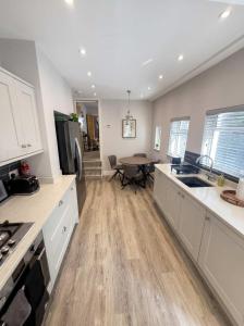 a kitchen with white cabinets and a table in it at Bright 2-Bed Garden Flat Central Guildford in Purley